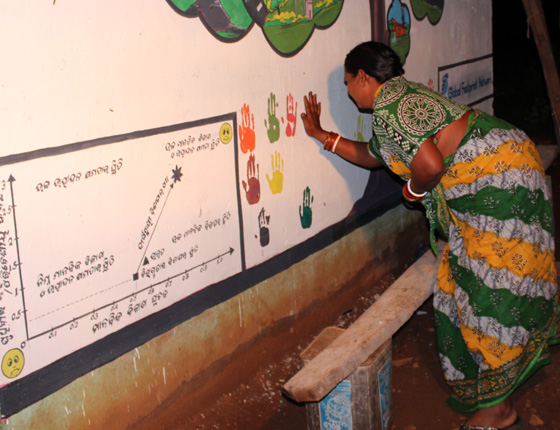 woman adding her handprint to board of colorful handprints