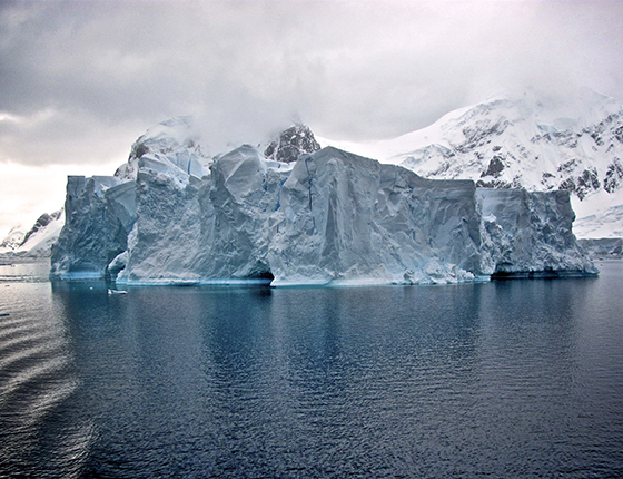 glacier in front of snow covered mountain with cloudy sky