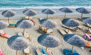 aerial view of umbrellas and lounge chairs on a beach in Greece